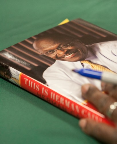 "This is Herman Cain!" A copy of "This is Herman Cain!" is shown as Herman Cain prepares to sign it.